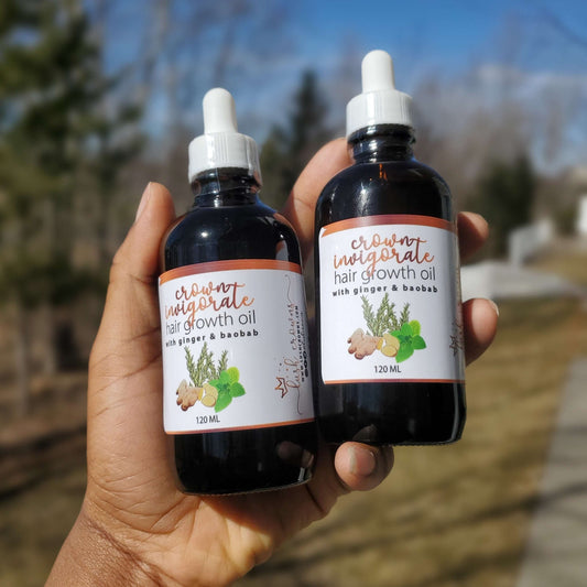 hand holding two bottles of Crown Invigorate Hair Growth Oil from Lush Crowns